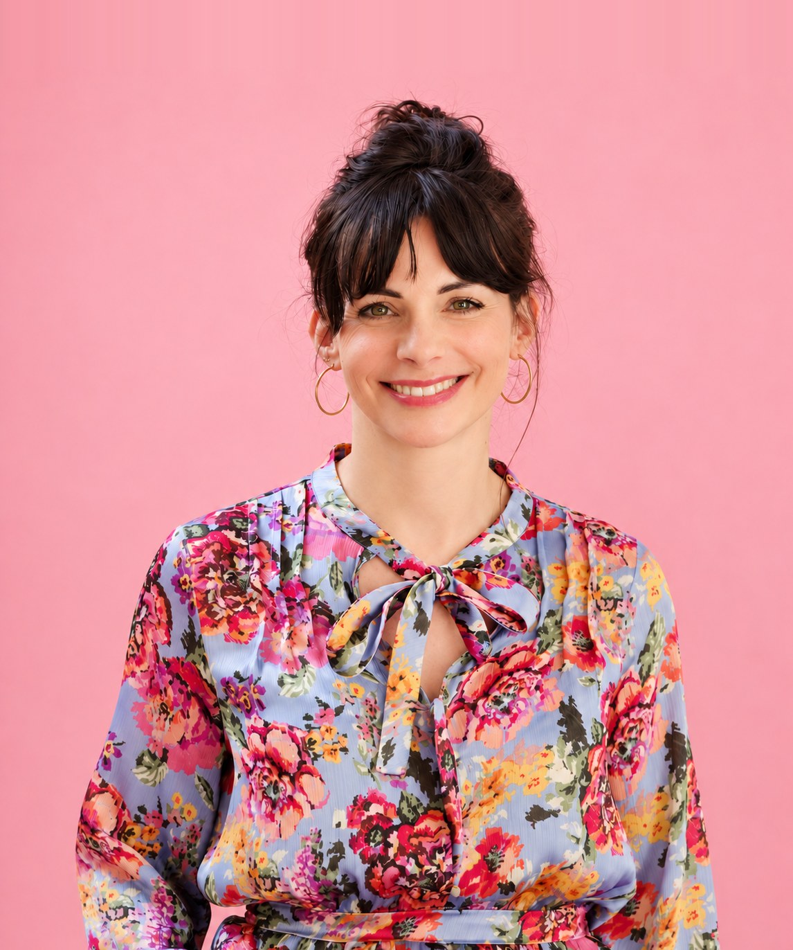 Maud Simon, souriante, en chemisier fleuri sur fond rose